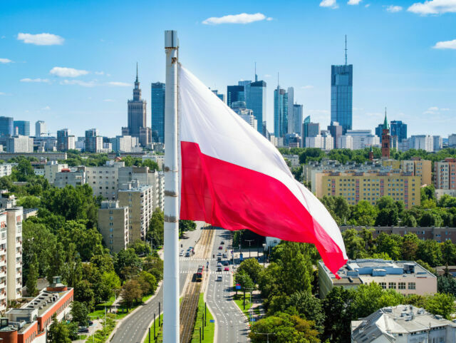 Polska flaga narodowa na tle wieżowców w Warszawie.