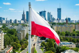 Polish national flag against skyscrapers in Warsaw city center, aerial landscape under blue sky