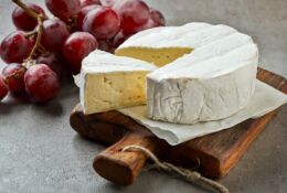 Ser camembert na drewniane desce. Obok winogrono.