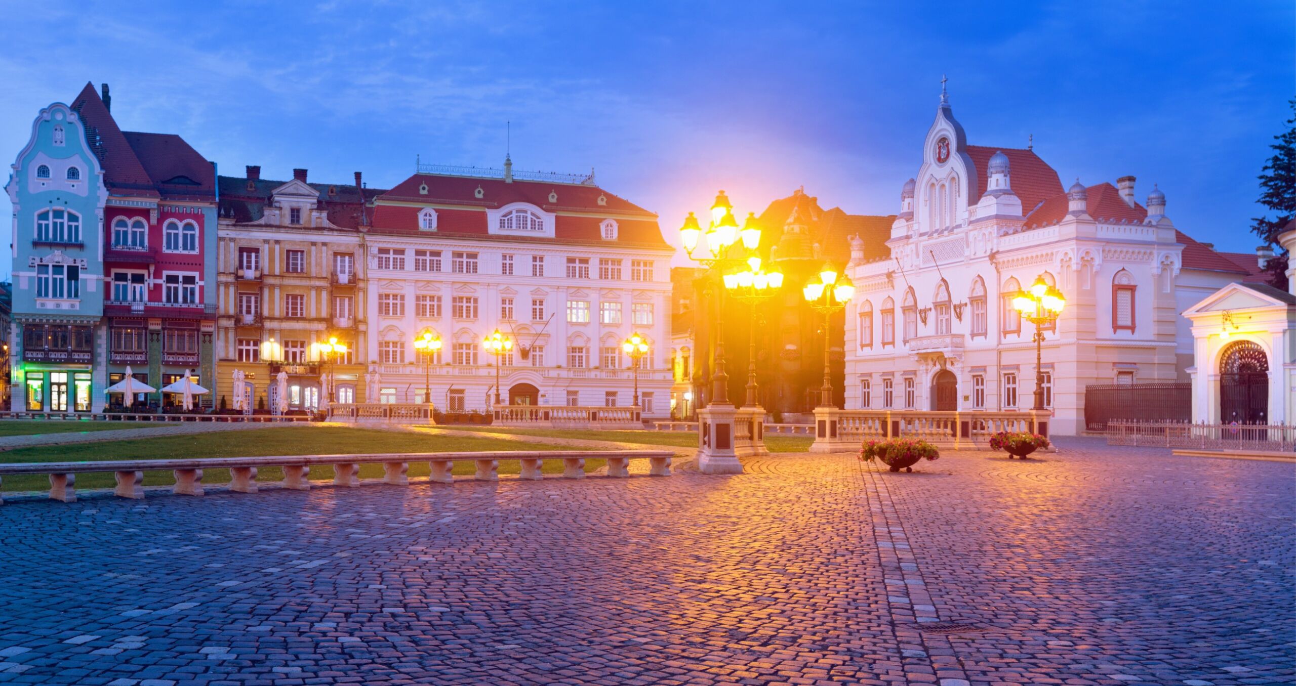 Oświetlony plac Unirii w Timiszoarze o zmierzchu