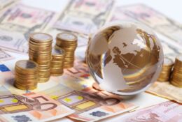 Glass globe on euro banknotes, next to piles of coins