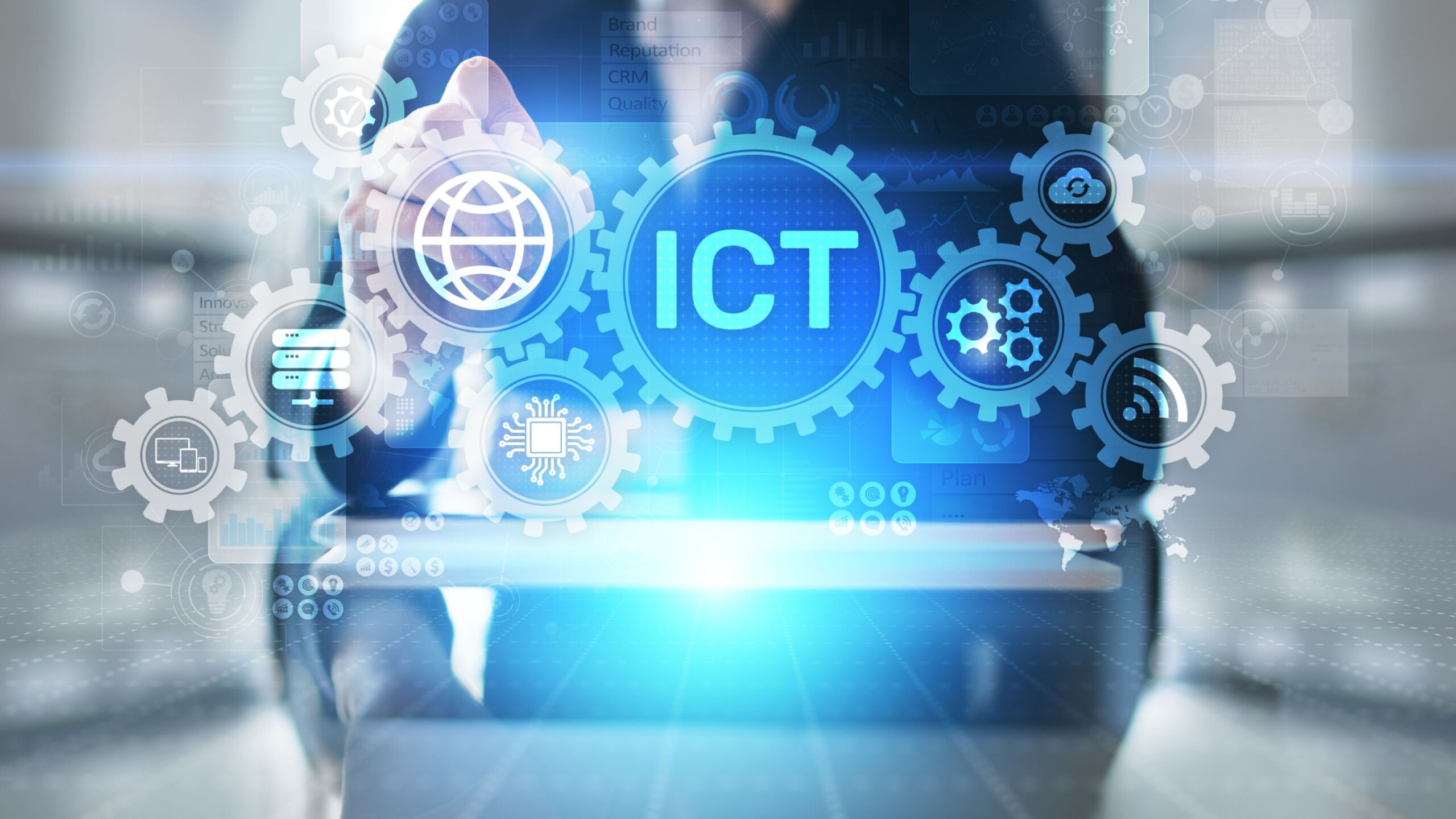 ICT - ikony na monitorze, z tyłu sylwetka mężczyzny w garniturze