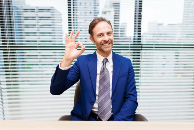 Mężczyzna w garniturze pokazuje gest ok